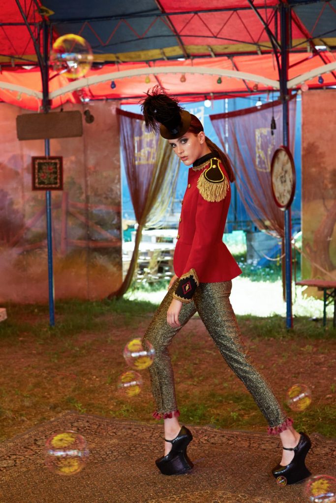 woman is walking through circus tent in extravagant outfit;